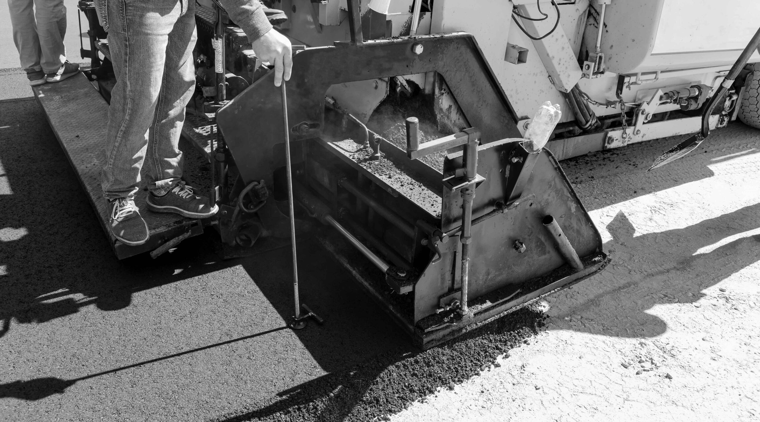 A steam roller and an asphalt paver machine are used during the construction of a new road as part of the layering process