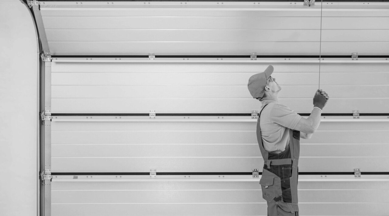 Automatic Residential Garage Doors Installation Performed by Professional Caucasian Technician in His 40s.